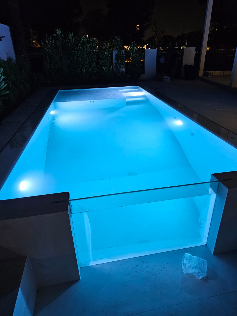 Glowing blue pool at night with surrounding area dimly lit